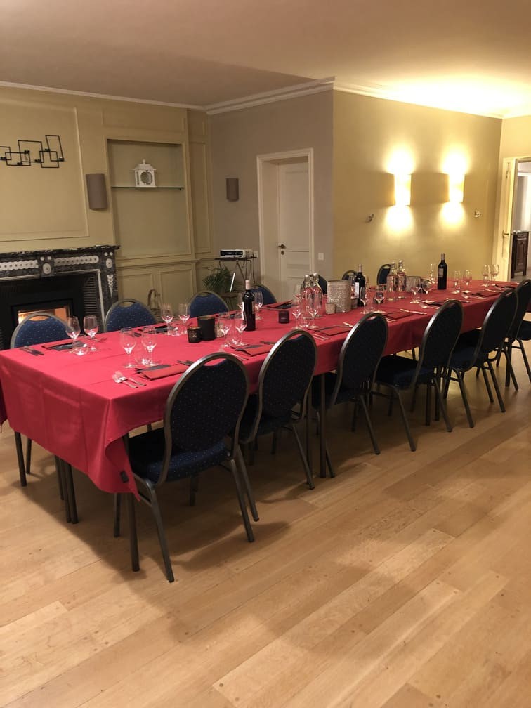 Grande salle avec grande table devant le feu